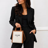 Model carrying the Celine Small Vertical Cabas in natural canvas with tan leather, styled with a black suit